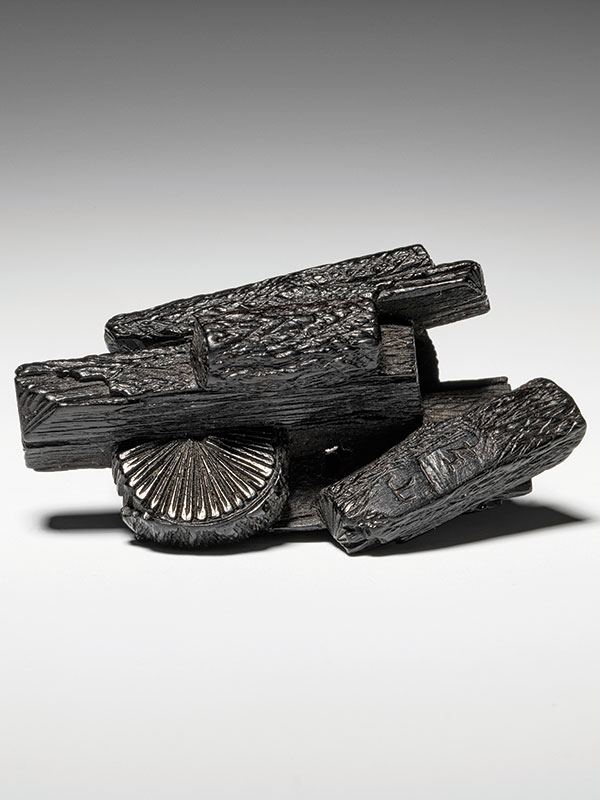A dark cherrywood carving of a bundle of charcoal